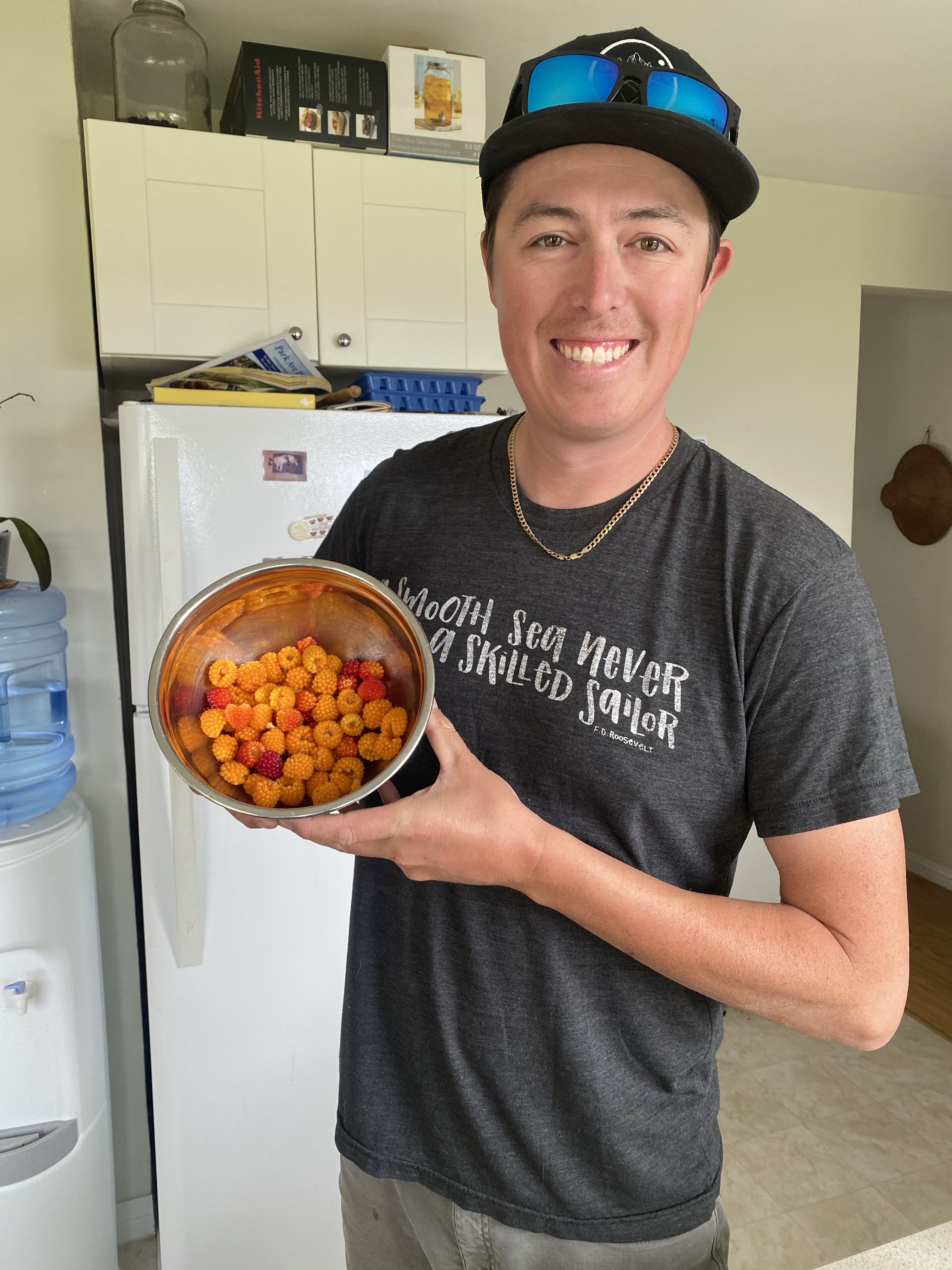 Man smiling holding a metal bowl full of ma̱ḵ'ooxs