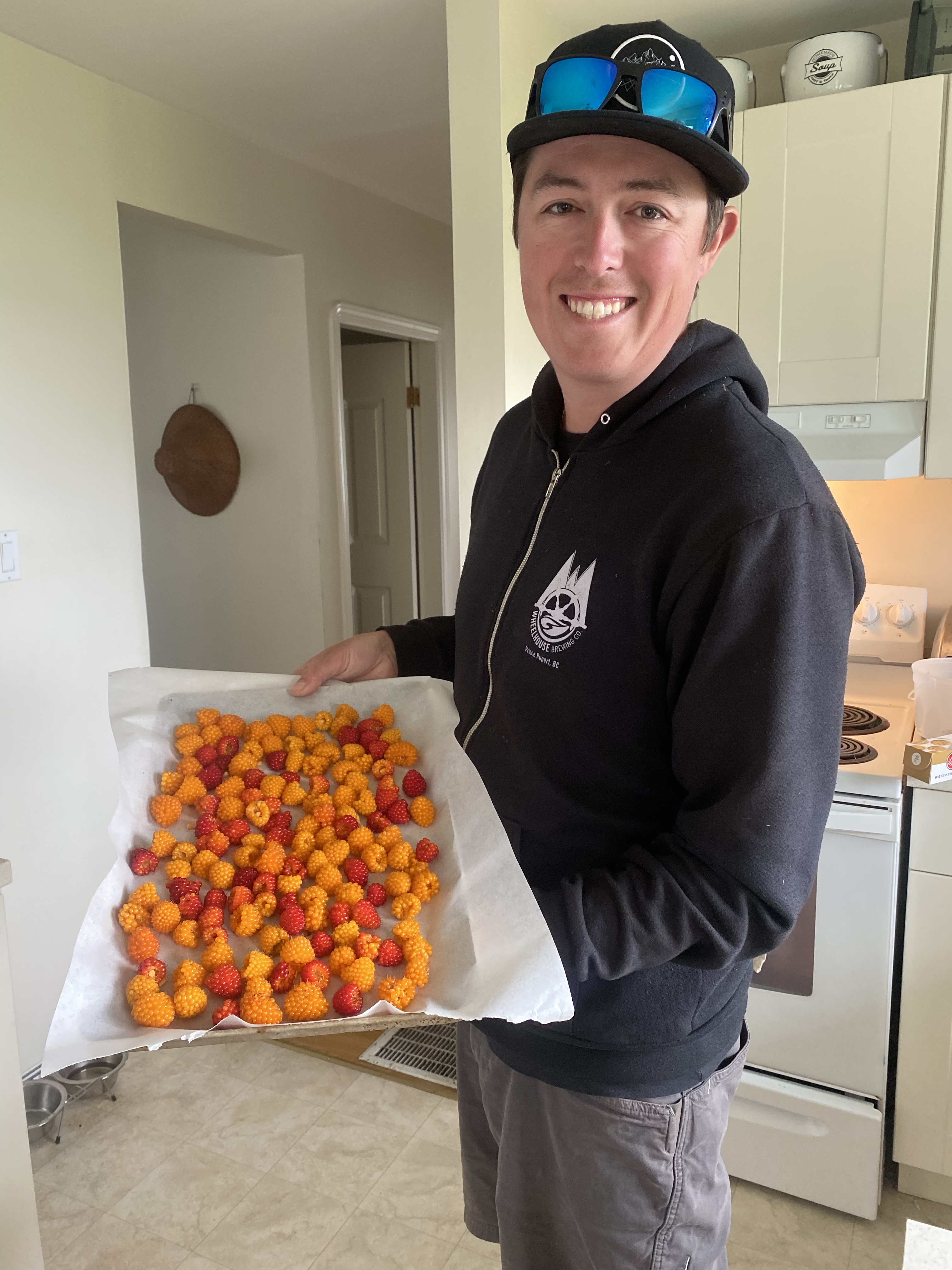 A man holding a single layer of ma̱ḵ'ooxs on a lined cookie sheet
