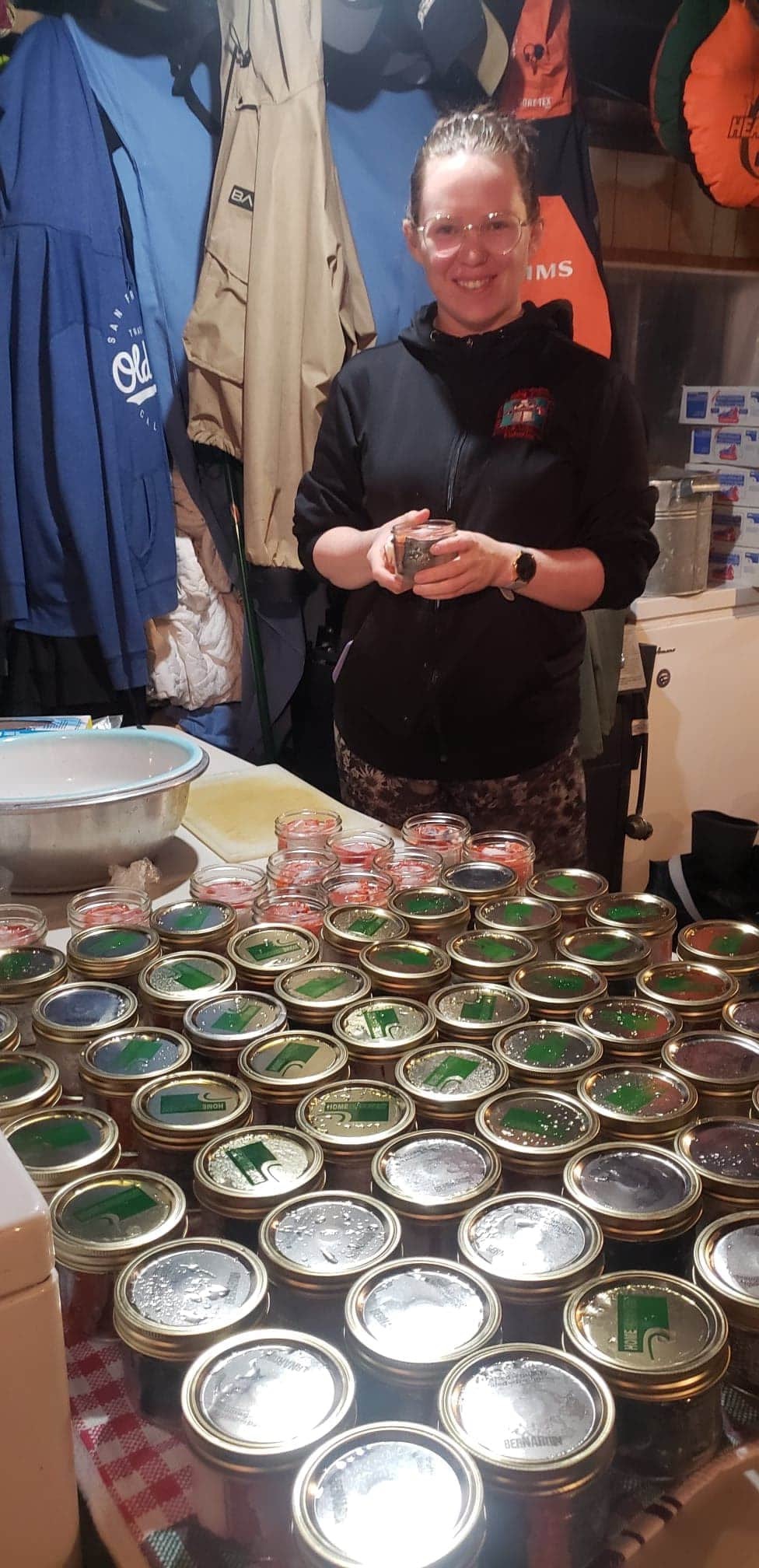 A lady holding a jar with many jars on the table