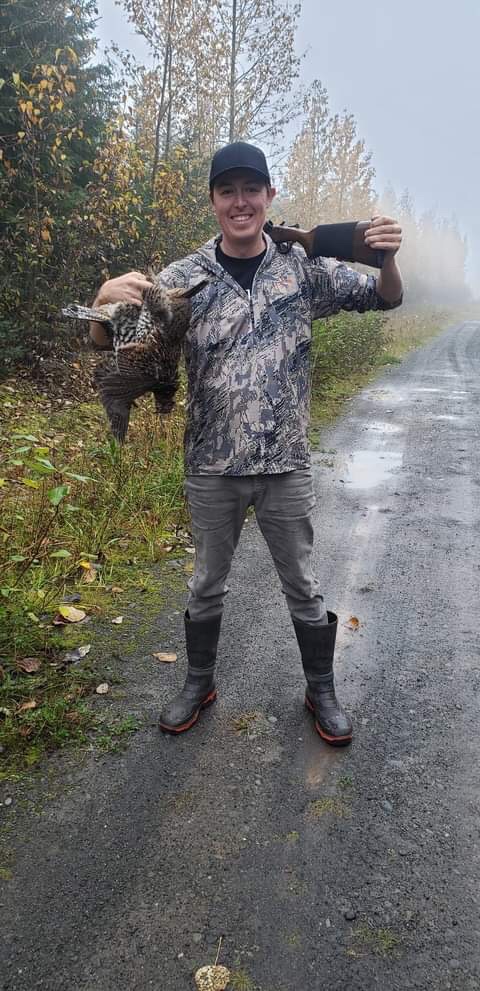A man holding ma̱xmeex and a hunting gun