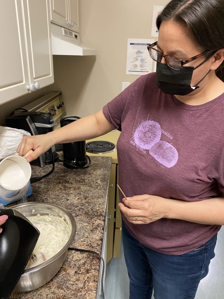 person pouring sugar into the whipped 'as